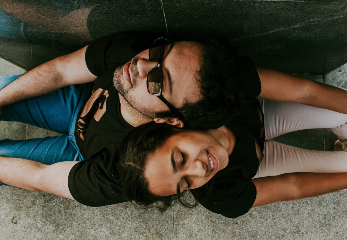 A couple enjoys a tranquil moment sitting back to back with eyes closed.